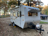 This Starcraft AR-ONE travel trailer RV rental is set up at a quiet, leaf-covered campsite, perfect for fall adventures.