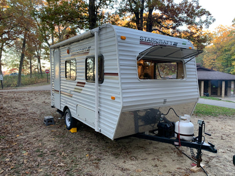 This Starcraft AR-ONE travel trailer RV rental is set up at a quiet, leaf-covered campsite, perfect for fall adventures.