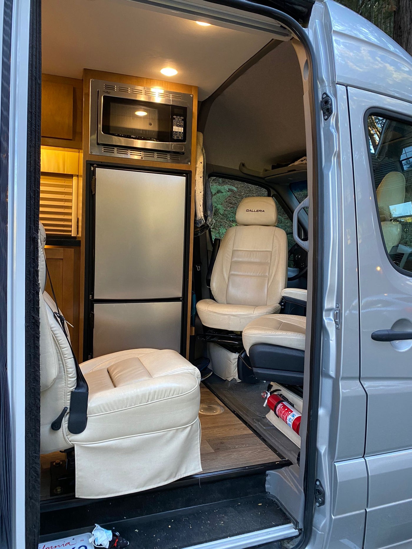  and people enjoying the desert evening amidst tents and vehicles.|View into an rv rental: a light-colored Galleria camper van interior with a compact kitchen (microwave — photo 1