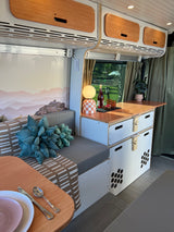 Step inside this cozy rv rental, showcasing a modern interior with kitchen, comfortable seating, and scenic window views.
