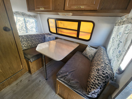 Cozy RV rental dinette area with table, patterned cushions, and warm lighting. Perfect for road trip meals.