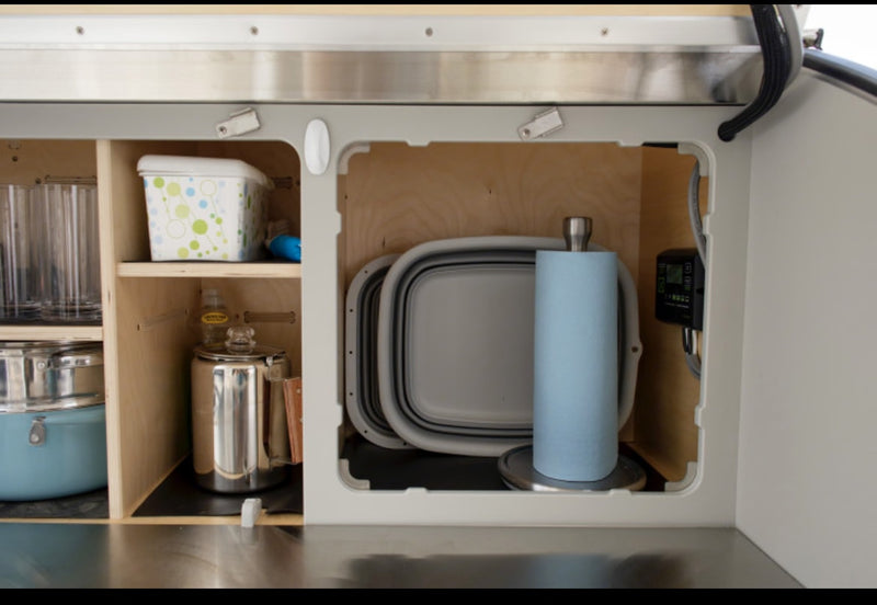 RV rental: Organized compact kitchen space with cookware, glasses, paper towels, & collapsible dishes. — photo 11