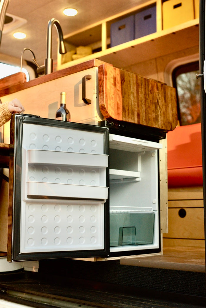  and rear windows revealing a road. Van life comfort.|Smiling woman relaxes in a cozy RV rental camper van at night