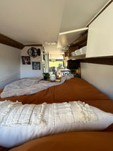 Cozy RV rental interior with a comfy bed, kitchen, and personalized pet portraits, offering a perfect travel escape.