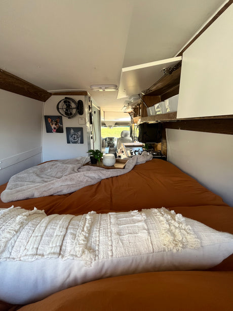Cozy RV rental interior with a comfy bed, kitchen, and personalized pet portraits, offering a perfect travel escape.
