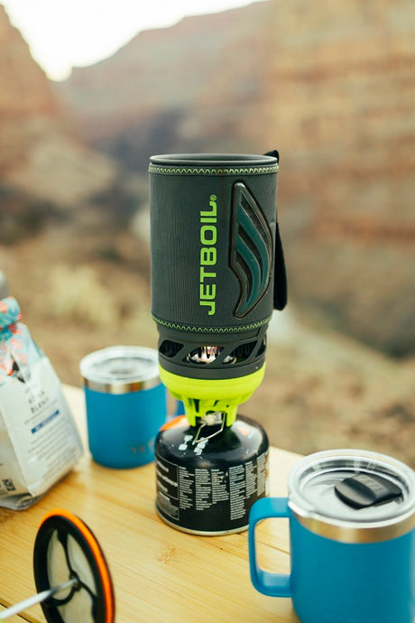 Outdoor coffee with Jetboil stove, mugs & coffee on a table. Perfect for your RV rental adventure.
