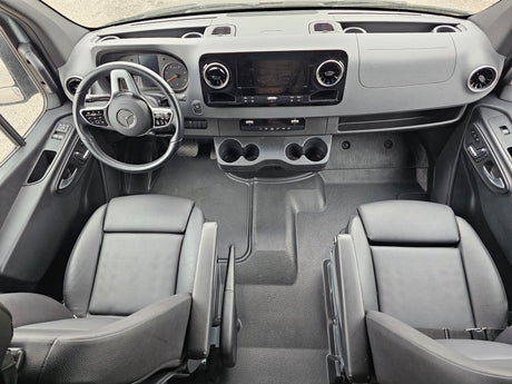 Modern rv rental van cockpit: dashboard, Mercedes steering wheel, infotainment, dual seats, and cup holders visible.