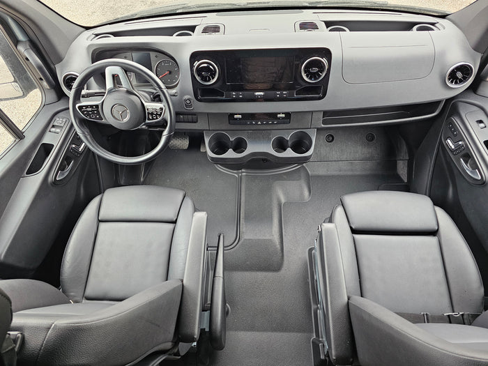 Modern rv rental van cockpit: dashboard, Mercedes steering wheel, infotainment, dual seats, and cup holders visible.