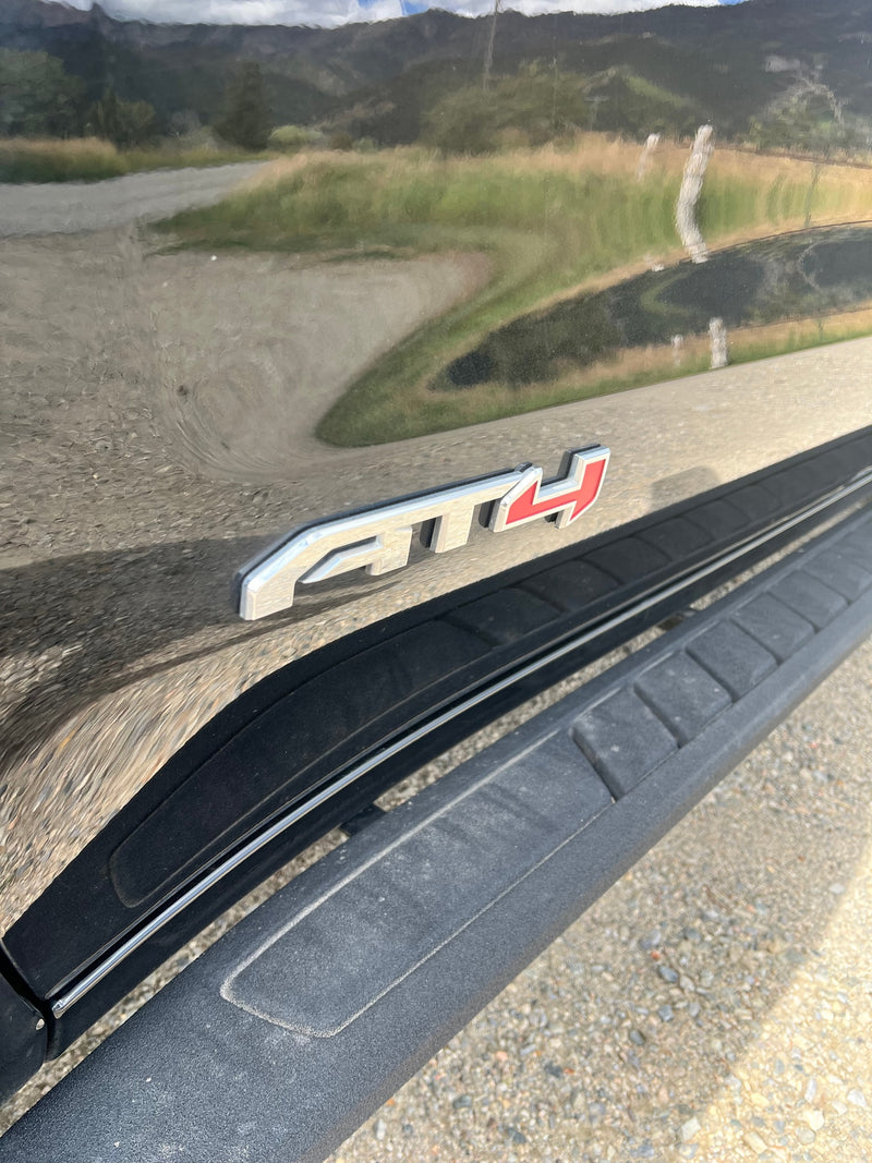 Shiny black GMC AT4 truck for RV rental, reflecting mountains & road. Includes running board for easy access. — photo 6