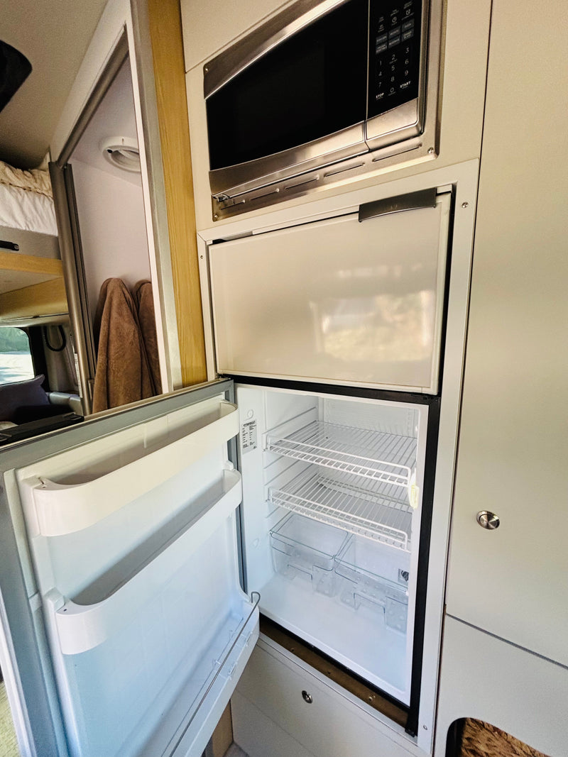 Inside this RV rental: An open refrigerator and freezer, with a microwave above, ready for your road trip adventures. — photo 3