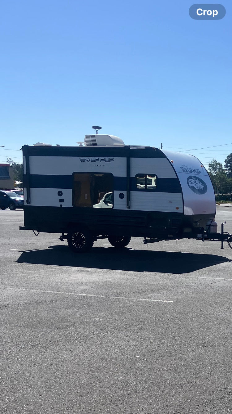 RV rental: A compact, black and white Wolf Pup travel trailer is parked outdoors on asphalt under a blue sky. — photo 3