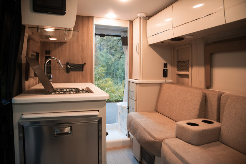RV rental: Modern interior with functional kitchen (sink, stove, fridge) & plush sofa with cupholders, plus outdoor view. — photo 13