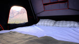 Experience scenic camping. This RV rental features a cozy tent interior with a comfy bed and breathtaking desert mountain views.