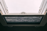 Bright RV rental interior looking up at a white roof vent. A dark mesh insect screen is pulled across.