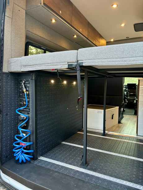 Inside this RV rental: versatile elevated bed, outdoor shower, & organized utility panel for your adventures.