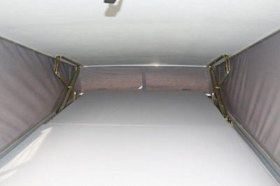 RV rental's pop-top interior, showing mattress, fabric walls, and support frame for elevated sleeping.