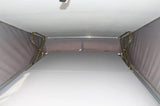RV rental's pop-top interior, showing mattress, fabric walls, and support frame for elevated sleeping.