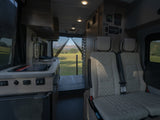 Modern RV rental interior: kitchen, comfy seating, and open back revealing a scenic view of fields and mountains.