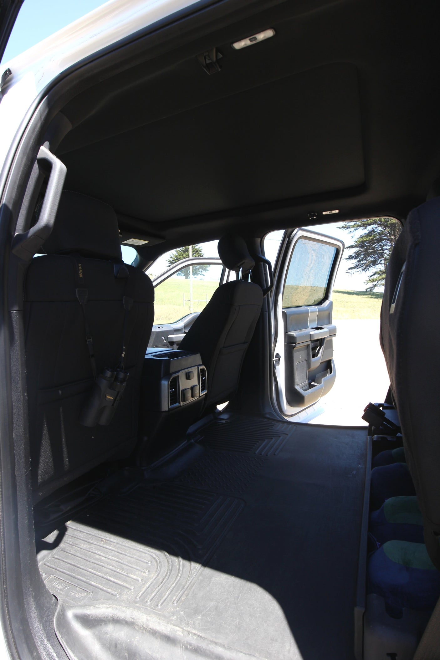 Spacious black truck interior, rear seats folded flat for ample cargo. Binoculars hang, ideal for an RV rental adventure.