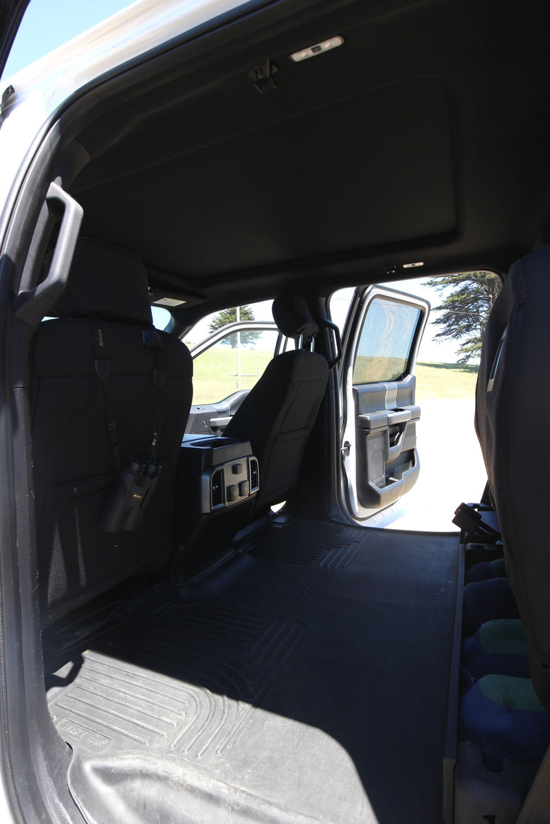 Spacious black truck interior, rear seats folded flat for ample cargo. Binoculars hang, ideal for an RV rental adventure. — photo 12