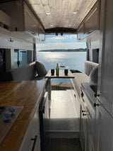 Stunning RV rental interior with a cozy dining area, kitchen, and panoramic ocean views for your next adventure.