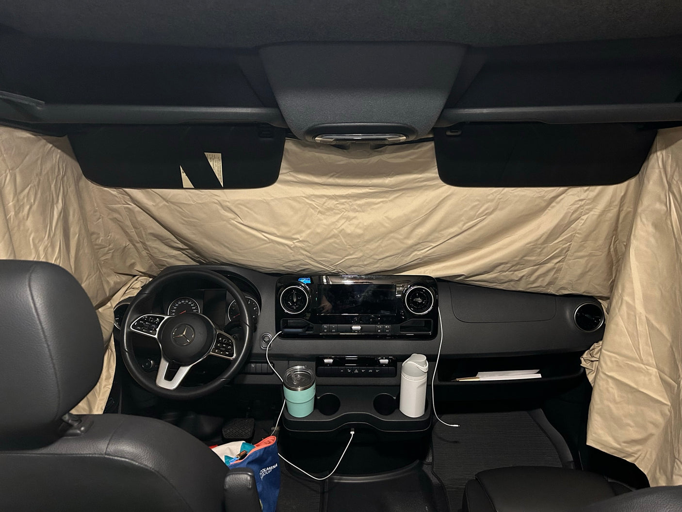 Inside an RV rental: Mercedes-Benz Sprinter driver's area with dashboard & privacy window shades.