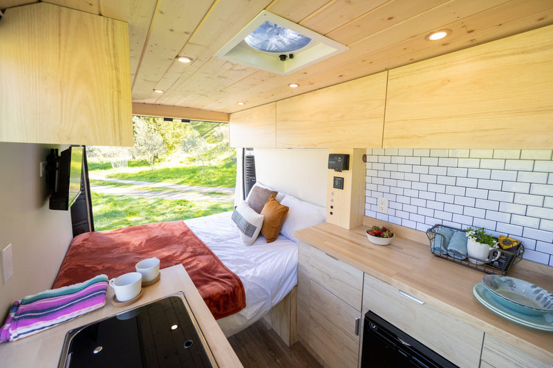  & scenic outdoor view through open doors.|Bright RV rental interior: A cozy bed — photo 4