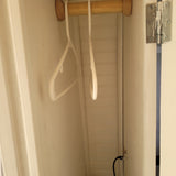 Inside an RV rental, a compact closet features a wooden hanging rod, two hangers, and wall paneling. Small yet functional.