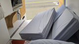 Experience mobile living: a compact RV rental interior with clever storage, folded cushions, and a view out the door.