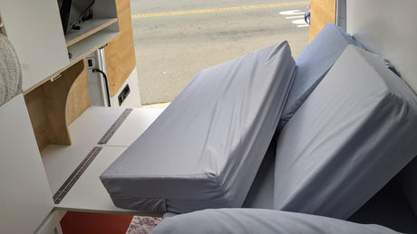 Experience mobile living: a compact RV rental interior with clever storage, folded cushions, and a view out the door.