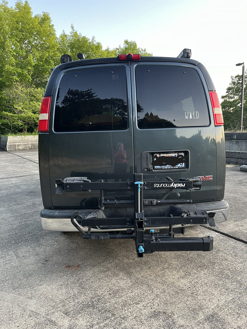 Rear of a dark GMC van with a bike rack & "WILD" decal, perfect for an rv rental outdoor escape. — photo 14