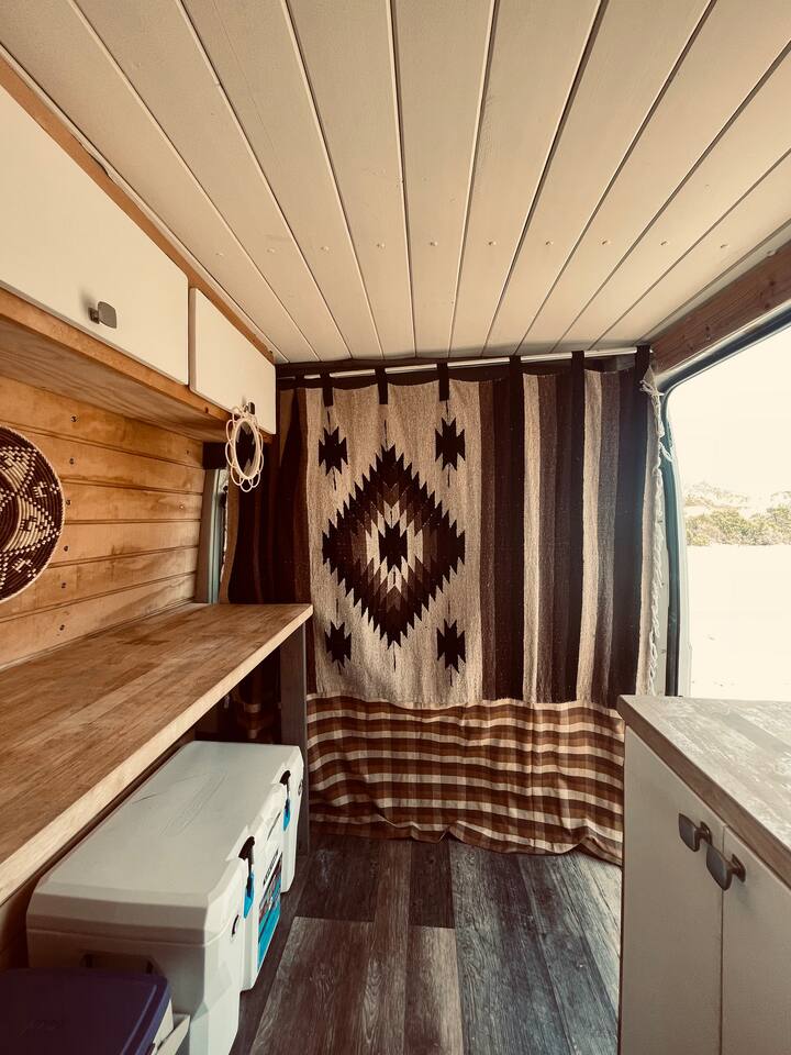 Experience comfortable RV rental travel in this custom van! Features cozy wood paneling, unique textile divider, and smart storage. — photo 12
