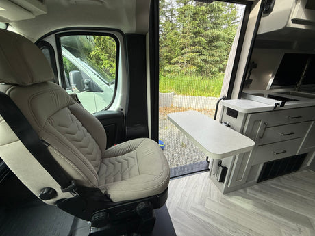Inside an rv rental: swiveling seat, kitchenette, and a refreshing outdoor view through the screen door. Ready for adventure!