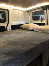 Cozy RV rental interior featuring a comfortable bed with pillows and bright LED lighting along the ceiling.