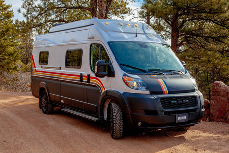 Adventure-ready custom camper van RV rental on a dirt road amidst pine trees. Perfect for your next outdoor road trip!