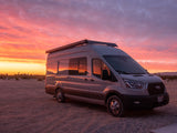 An RV rental camper van bathed in the vibrant hues of a desert sunset. Perfect for adventure!
