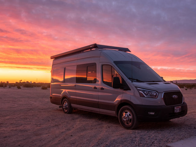 An RV rental camper van bathed in the vibrant hues of a desert sunset. Perfect for adventure!