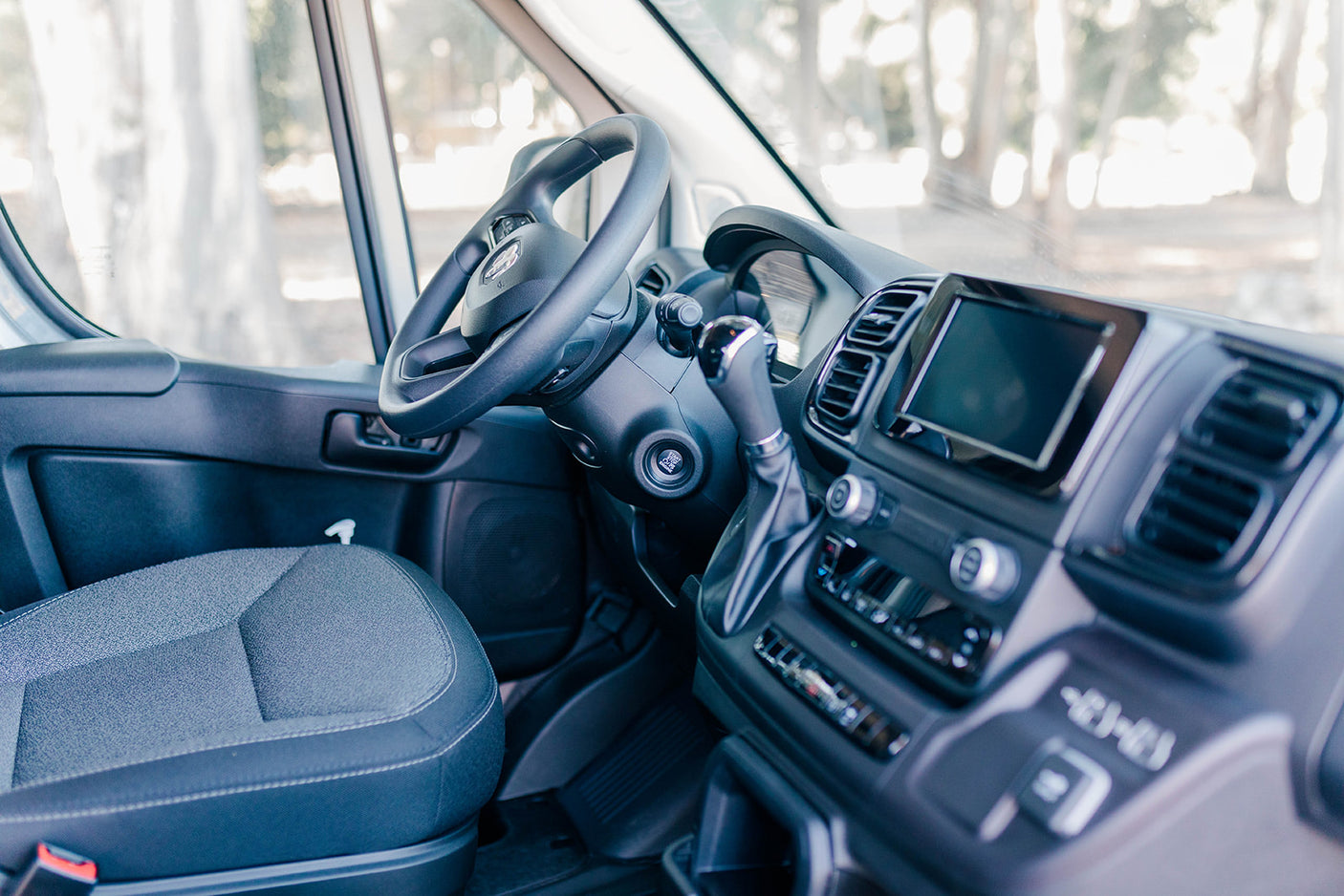 Explore the modern interior of an RV rental: driver's seat, steering wheel, and tech-equipped dashboard await your adventure.