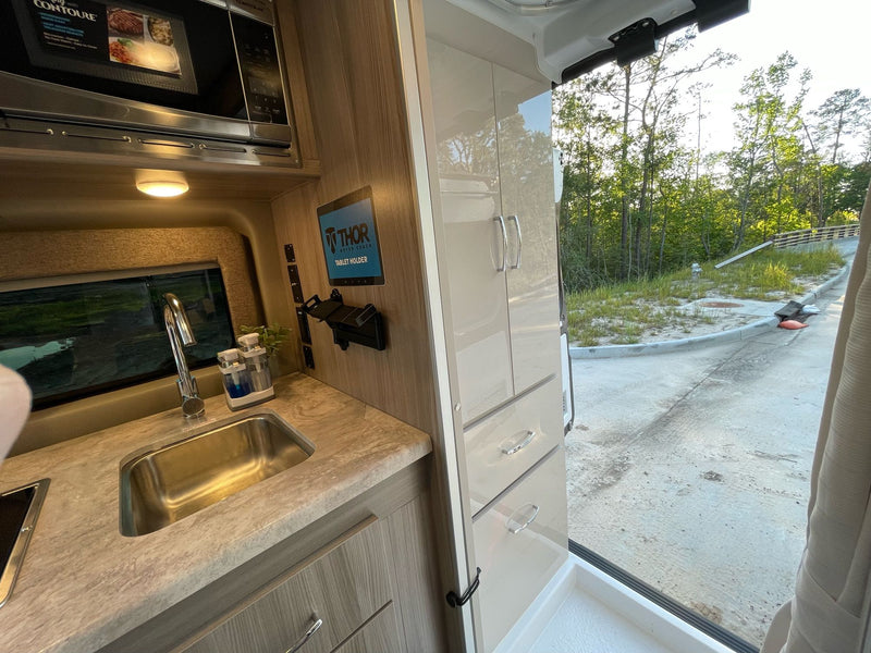 Compact RV rental kitchen area features a microwave, sink, and wood-grain cabinets. Perfect for mobile living. — photo 13