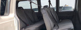 Inside an RV rental van showing worn grey passenger seats with seatbelts. View of other vehicles outside.