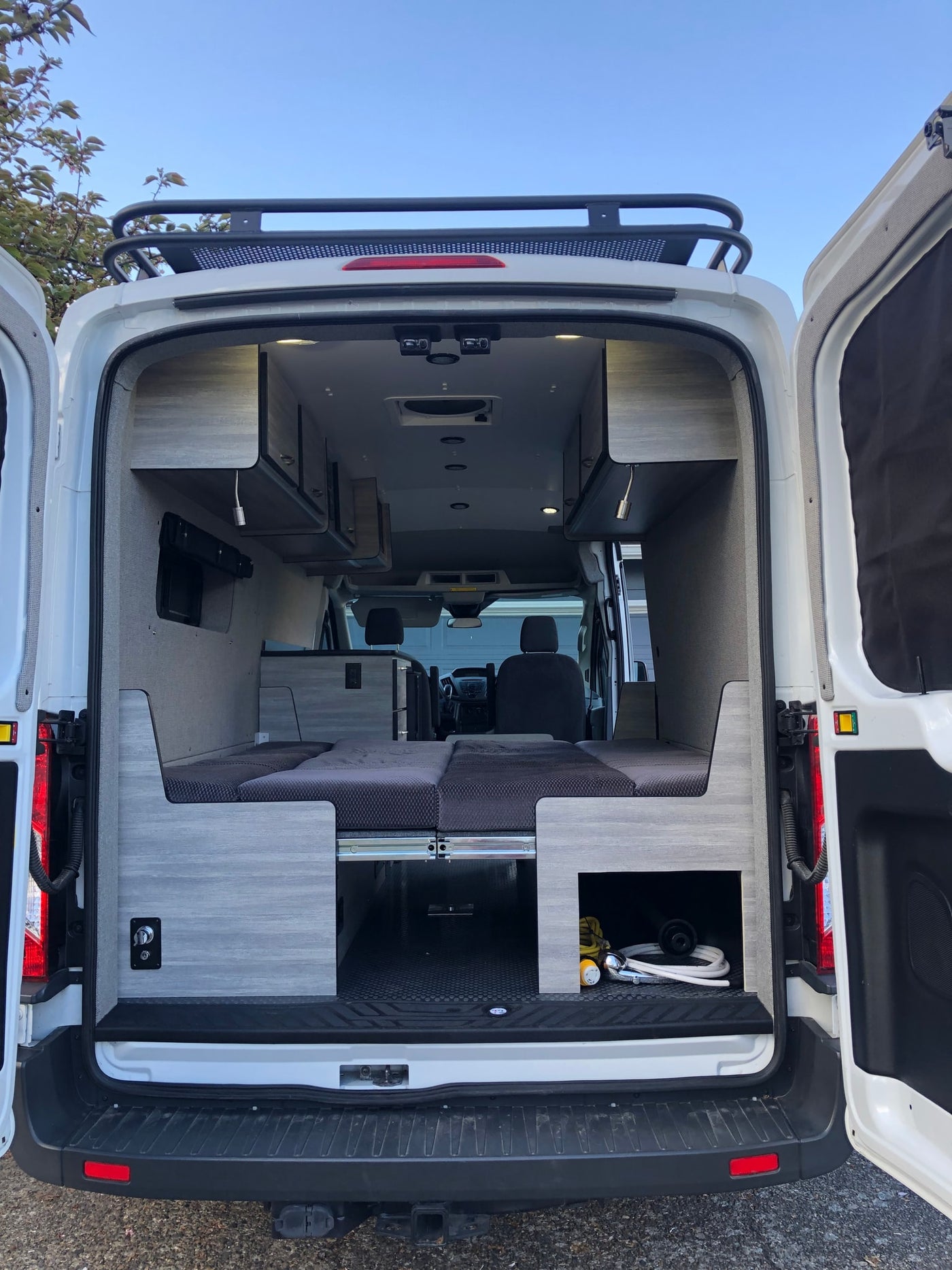 Discover this versatile RV rental: a modern camper van interior with modular bed, ample storage, and a roof rack. — photo 7