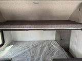 RV rental: Upper bunk bed with patterned mattress, lower bed covered in protective plastic, ready for your adventure.