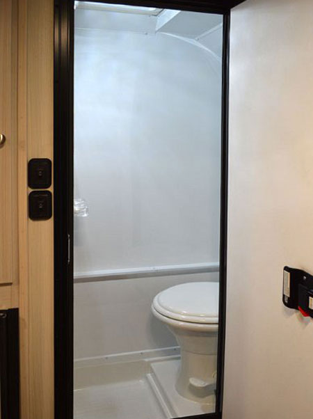 This rv rental features a compact white bathroom with a toilet and shower pan visible through the doorway.