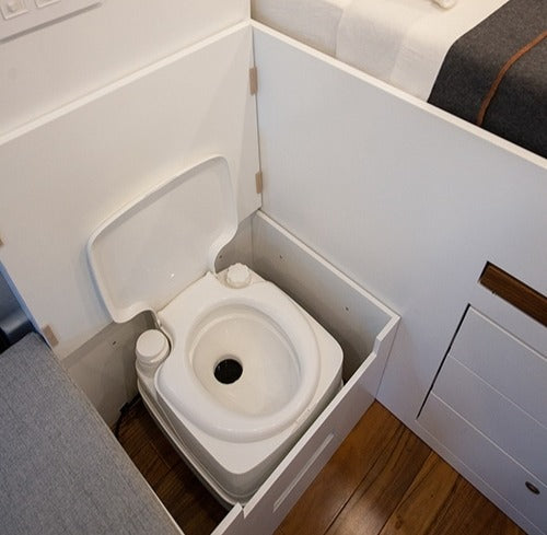 RV rental with a clever space-saving portable toilet integrated into white cabinetry, next to a sleeping area. Ideal for travel.