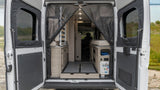 RV rental rear view: Open doors reveal a camper van interior with mesh screen, modular bed, storage, and utility panel.