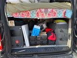 Organized **RV rental** interior with under-bed storage showing electrical, hoses, bags, and folding crates.