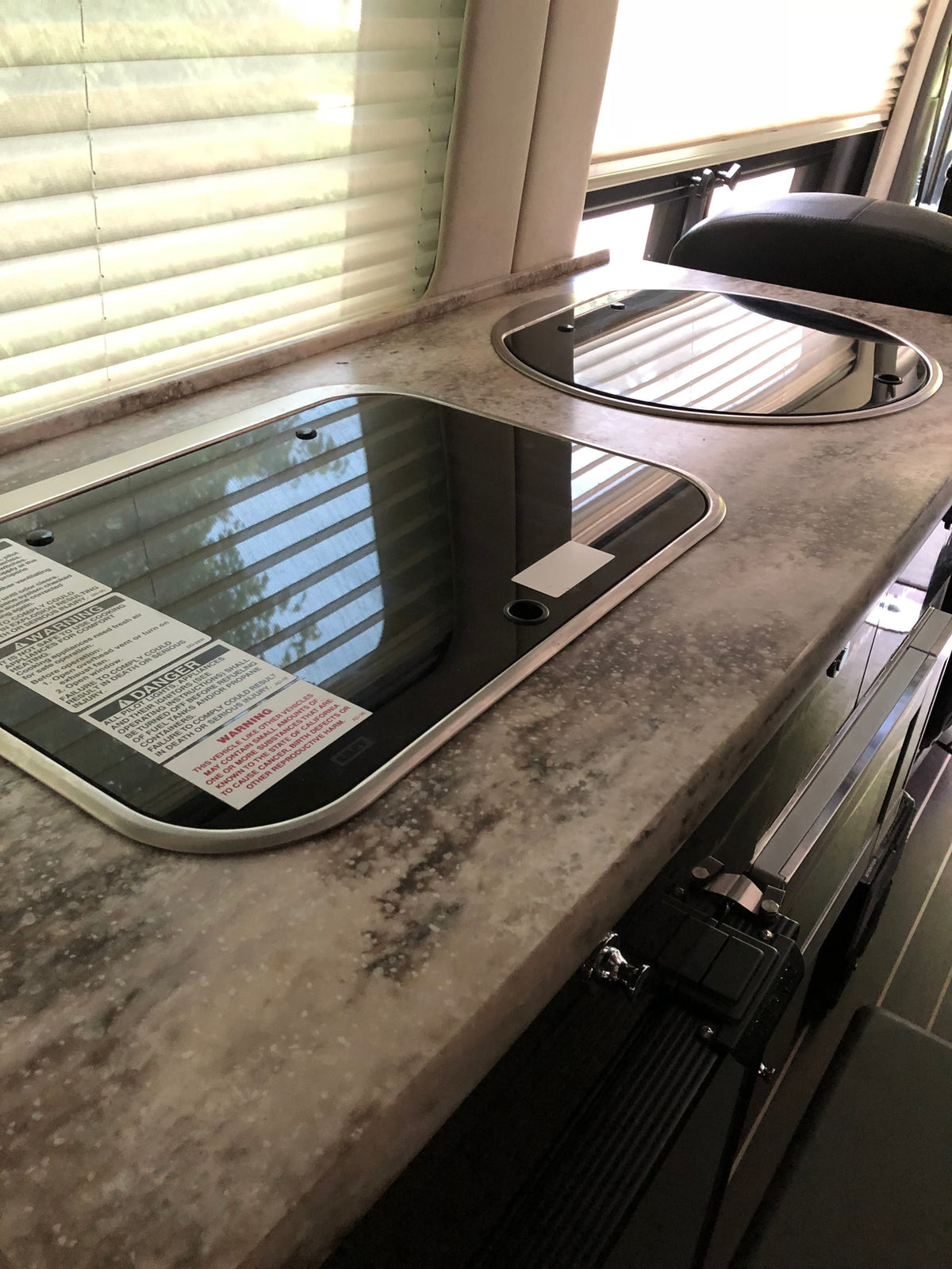  with warning label & decorative pillows.|RV rental interior featuring a large overhead screen & a small sun visor screen — photo 12