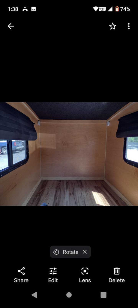 Empty RV rental interior features light wood walls, laminate flooring, and dark ceiling. Ready for your adventure.