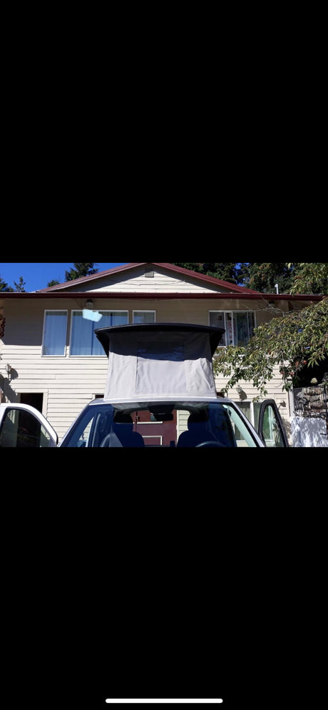 Pop-top camper van RV rental. White van with gray pop-top open, parked at a house on a sunny day. Ready for your adventure.