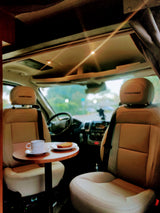 Roadtrek RV rental interior. Swivel seats, table with coffee & cake. Perfect start to a day of travel!